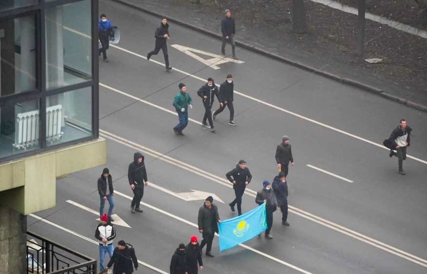 示威者举着国旗在阿拉木图街头游行。(2021年1月5日)